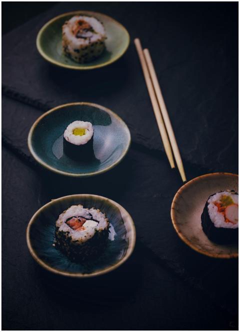 A variety of sushi rolls on ceramic plates, accomp