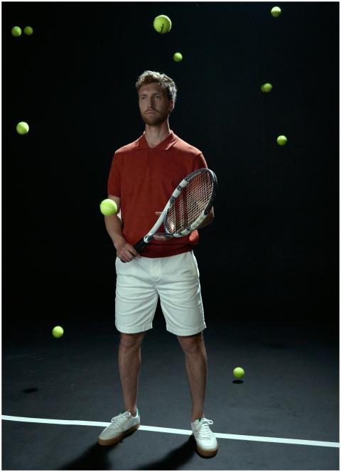 Tennis player in studio holding racket surrounded