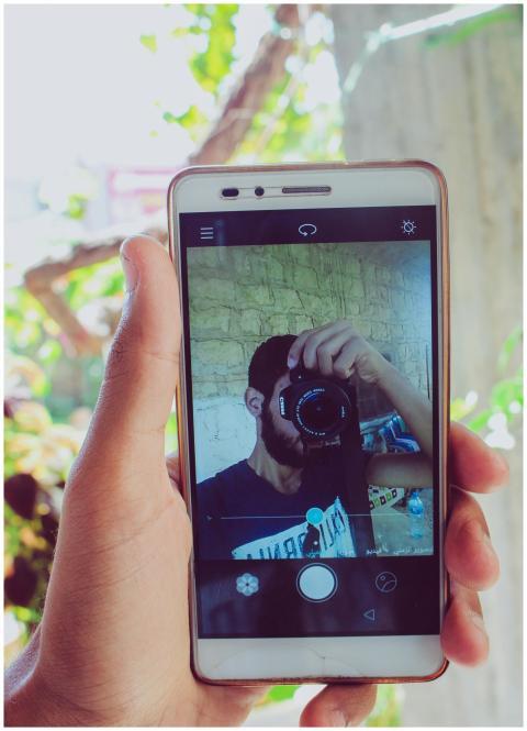 A person captures their reflection using a smartph