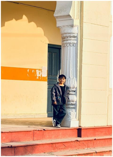 Young boy leaning against a decorative pillar in a
