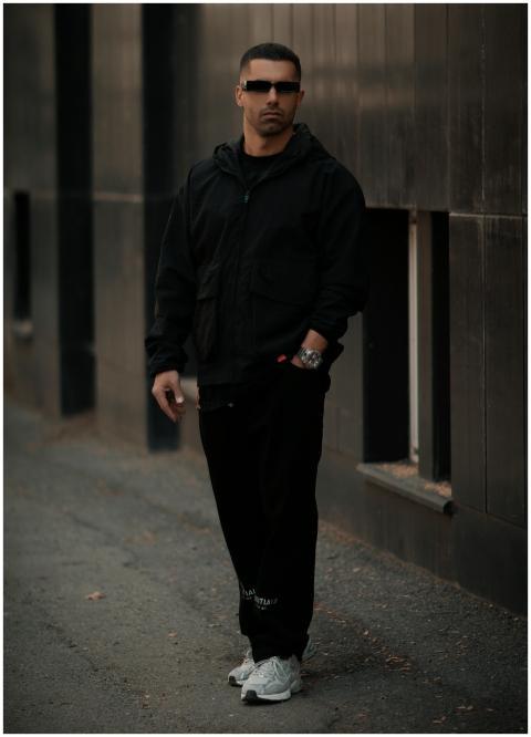 A fashionable man stands confidently in a dark urb