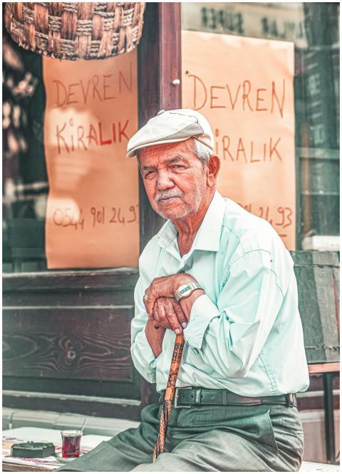 Elderly man with a cane sitting outdoors in Bolu,