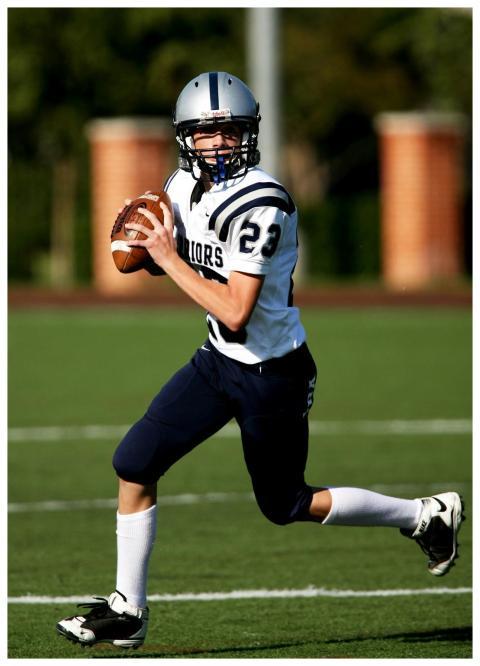 Young quarterback running with a football during a