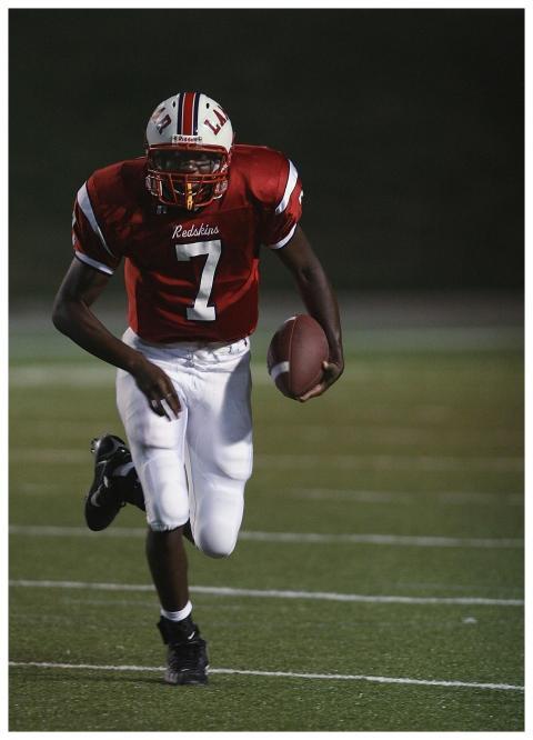An athlete in a red uniform running with a footbal
