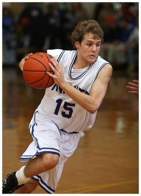 Teen male basketball player in action on indoor co