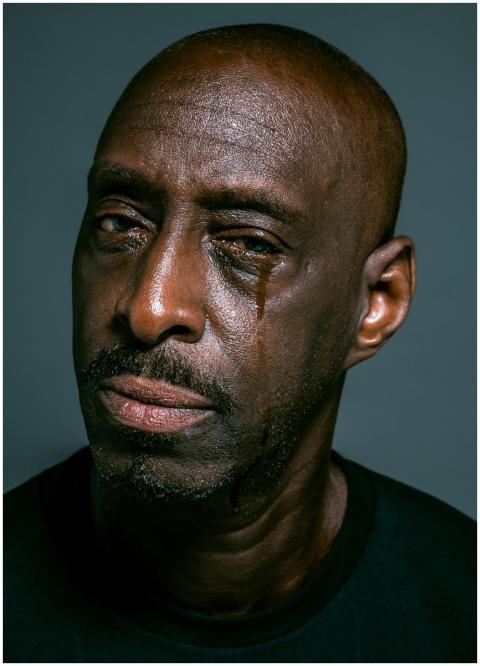 A close-up portrait of a man shedding a tear again