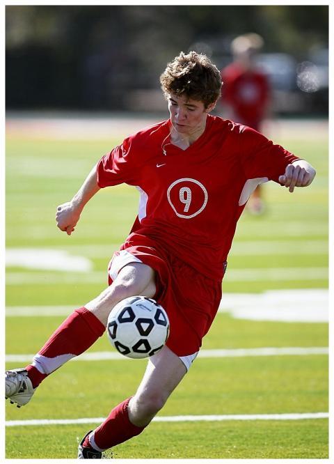 Soccer player in red uniform kicking ball during a