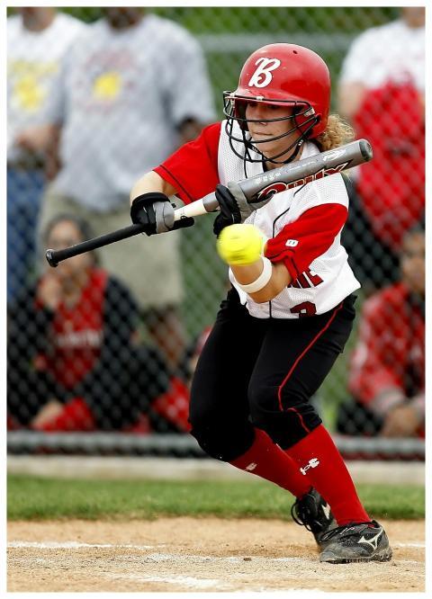 Focused female softball player in action swinging