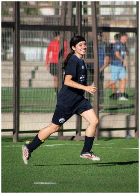 Young female soccer player in navy kit running on