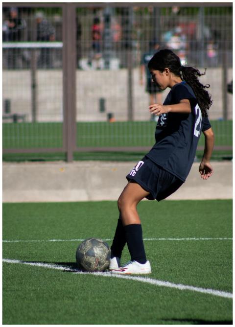 Young female soccer player controlling the ball on