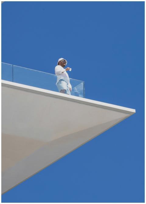 A person stands on a modern balcony against a clea