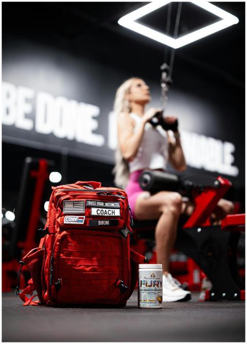 Focused woman lifting weights with a red backpack