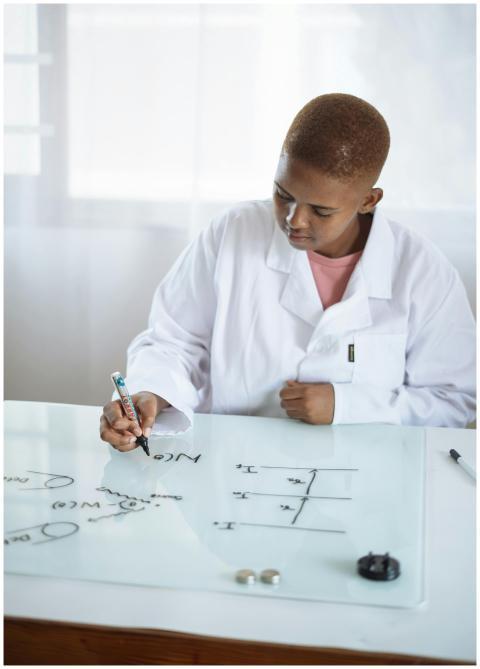 Young chemist in lab coat writing chemical formula