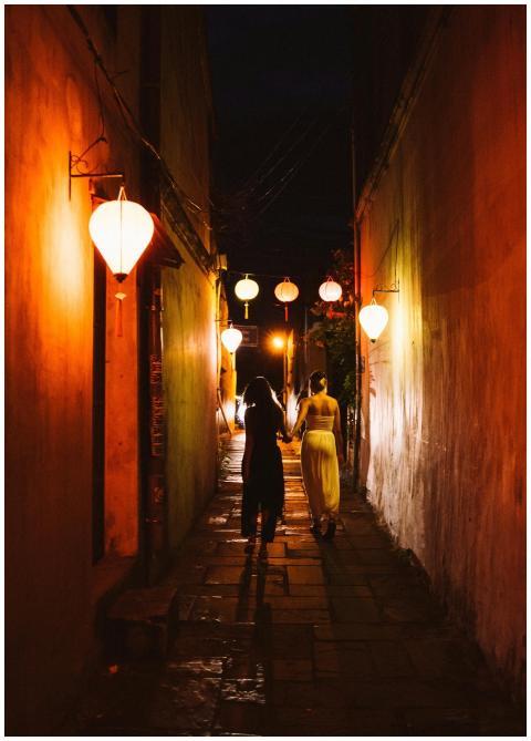 Two people walk hand in hand under decorative lant