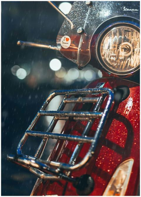Close-up of a classic red scooter in the rain, cap