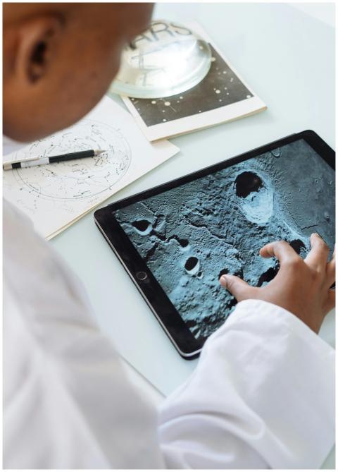 A student examines lunar craters on a tablet, embr