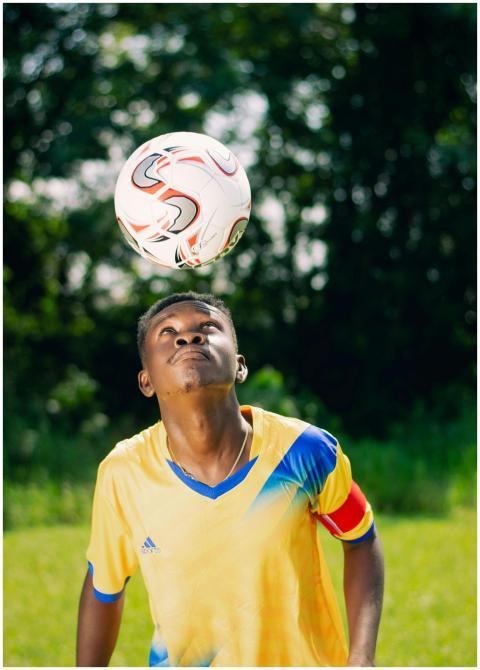 A young man skillfully balances a soccer ball on h
