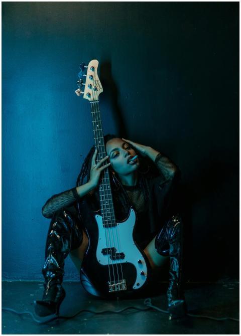 A fashionable woman poses with an electric guitar