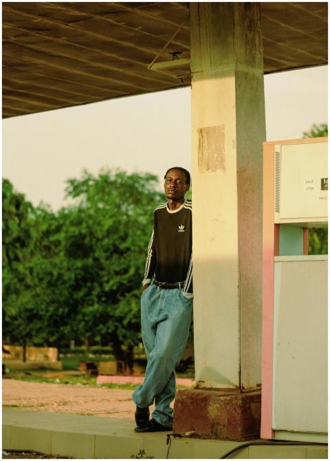 Young man in casual attire leaning against a gas s