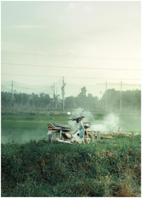 A vintage motor scooter parked in a misty countrys