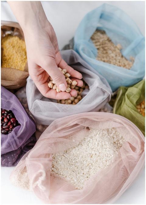 Hand holding chickpeas above colorful reusable bag
