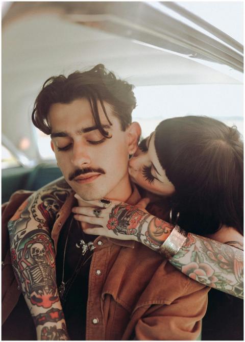 A tattooed couple shares an affectionate moment in