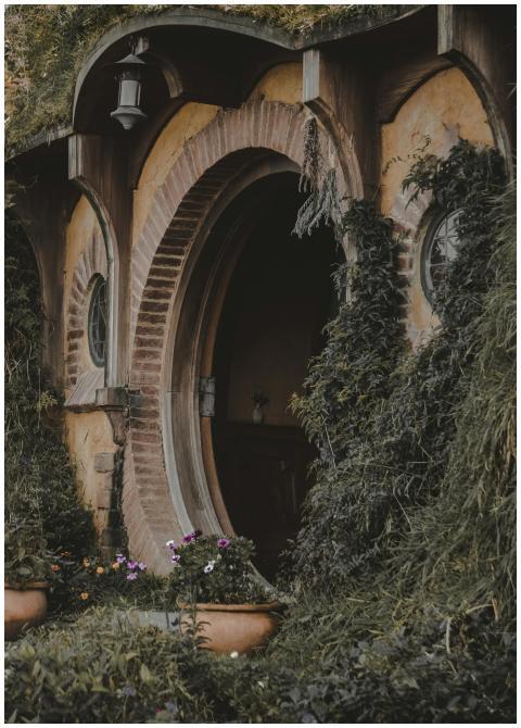 Round wooden door surrounded by vibrant greenery,