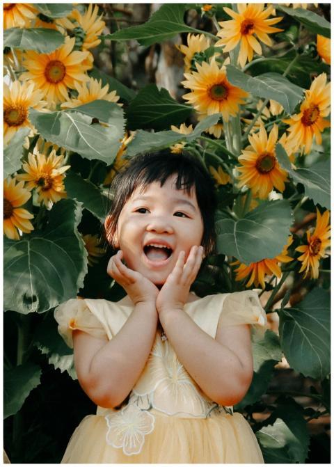 A young girl joyfully smiling amidst vibrant sunfl
