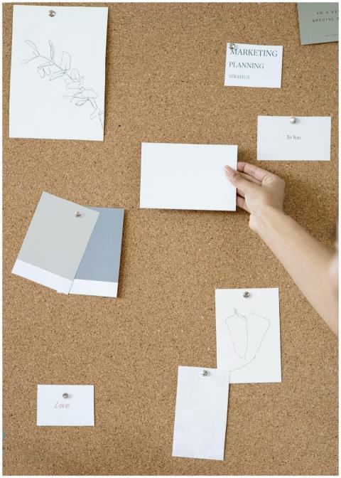 Corkboard with notes and hands showcasing creative