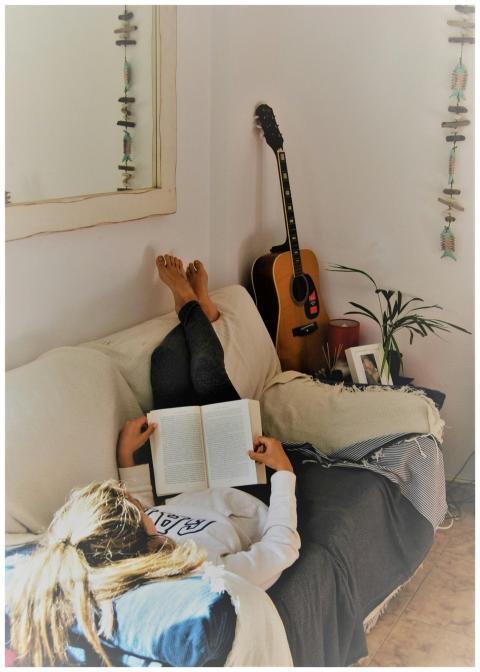 Woman relaxing on a sofa reading a book with an ac