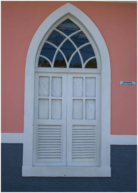 Elegant colonial-style arched window with pink wal
