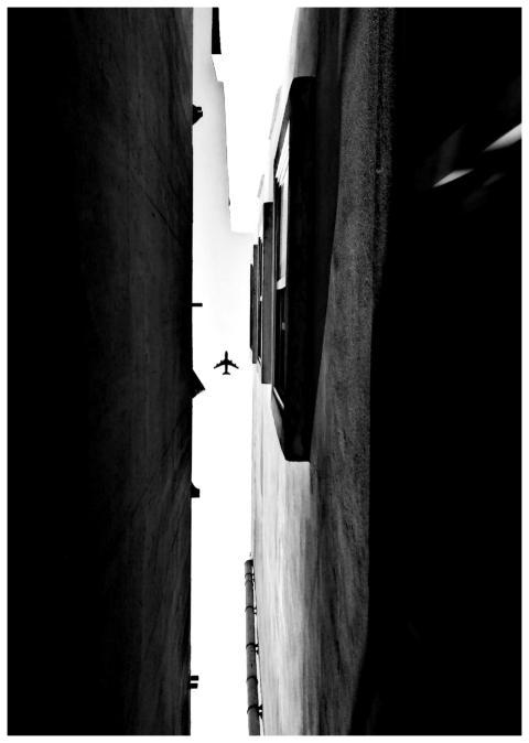 Silhouette of an airplane flying over narrow citys