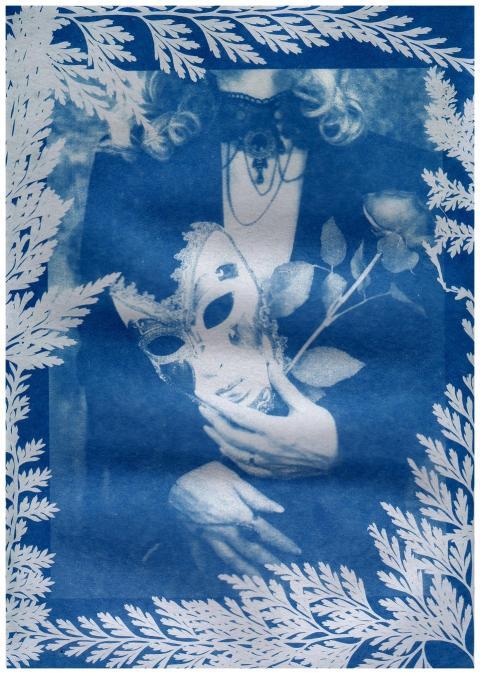 A cyanotype print featuring an ornate mask and ros