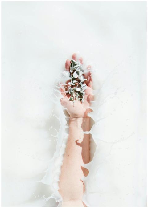 A hand gracefully holding flowers emerges from a s