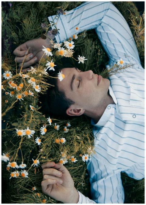 A man in a dress shirt lying in a chamomile field,
