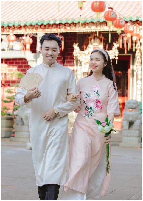 Happy couple in traditional dresses walking in a f