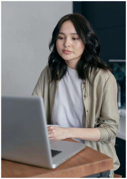 A young woman with black hair working on a laptop