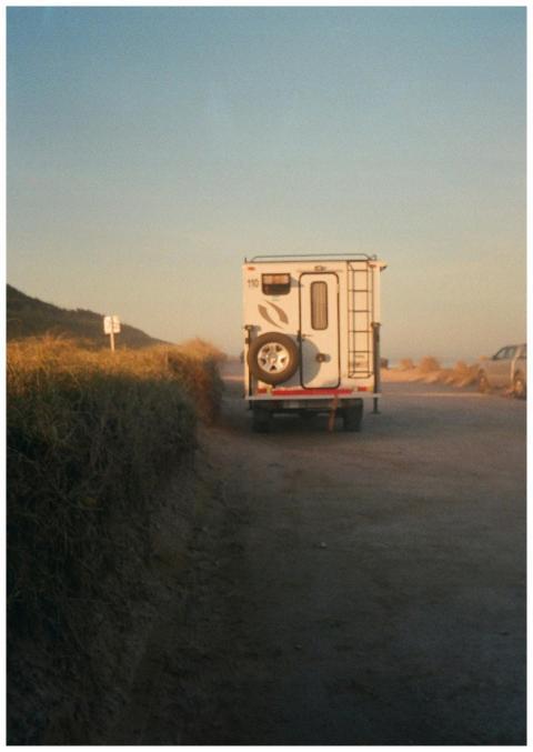 A van parked on a dirt road during sunset, with a