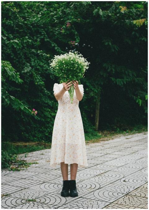 A girl in a white dress standing outdoors, holding