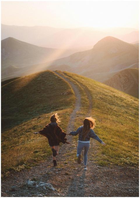 Two women running joyfully together on a scenic mo