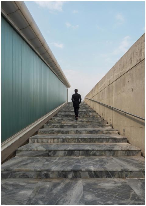 A lone business professional walks up a modern sta