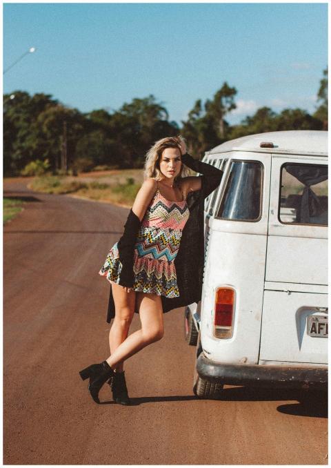 Stylish woman poses in a sundress by a vintage van