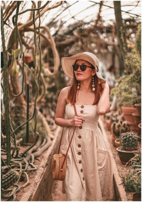 Stylish woman wearing a sun hat and dress walking