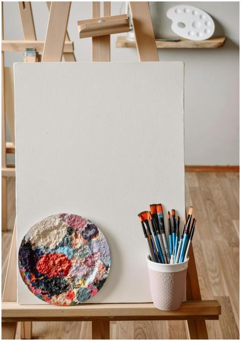 Artistic setup featuring a blank canvas, paint bru