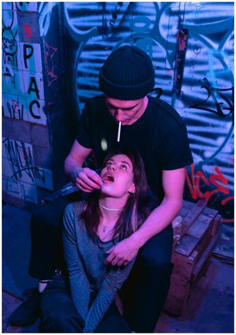 Young adults in graffiti-covered alley engaging in