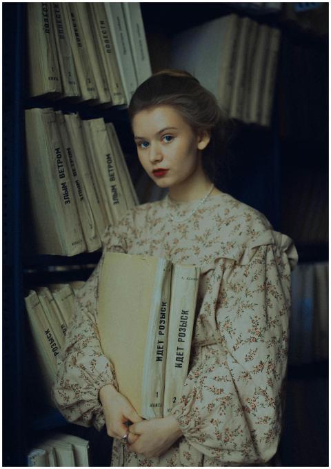 A woman in a floral dress stands in a library hold