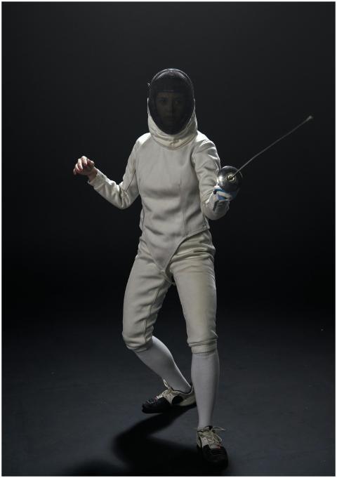 A female fencer skillfully posing with foil in ful