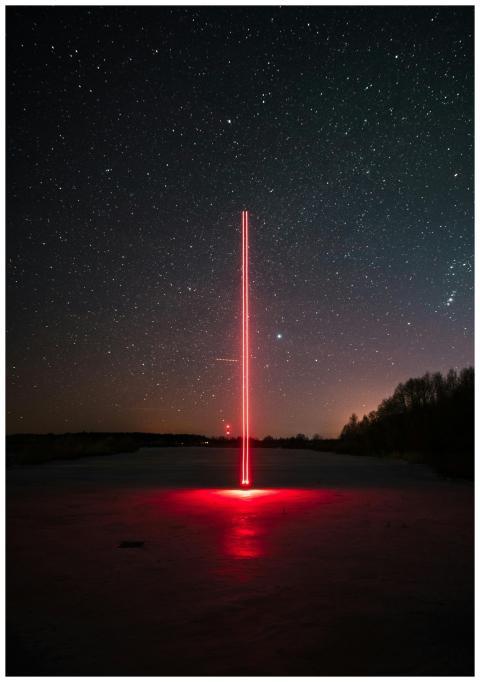 A striking red laser beam against a clear, starry