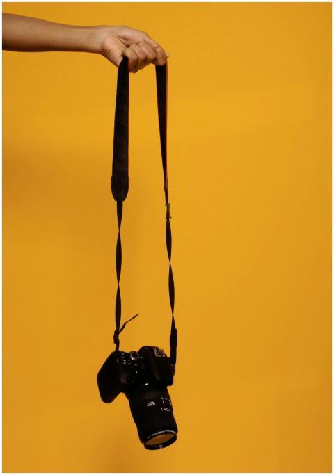 A DSLR camera suspended by hand against a vibrant