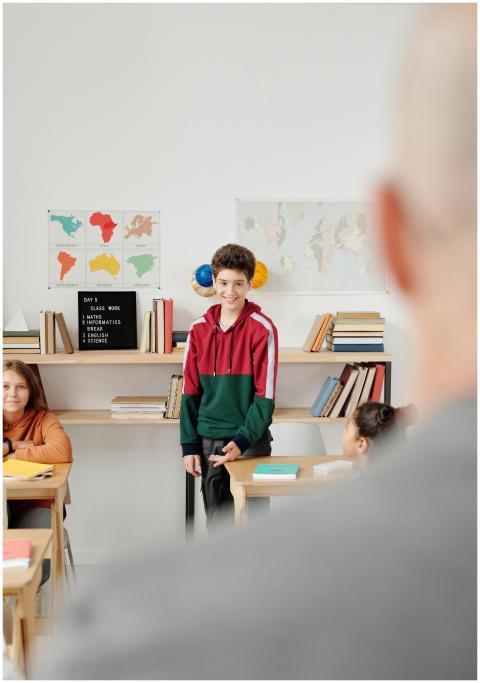A cheerful student stands in a classroom ready to